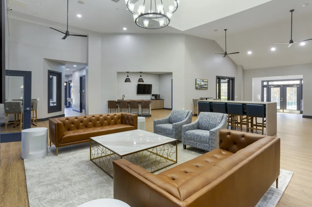 Clubhouse lounge with sofas and arm chairs, and a kitchenette with bar seating