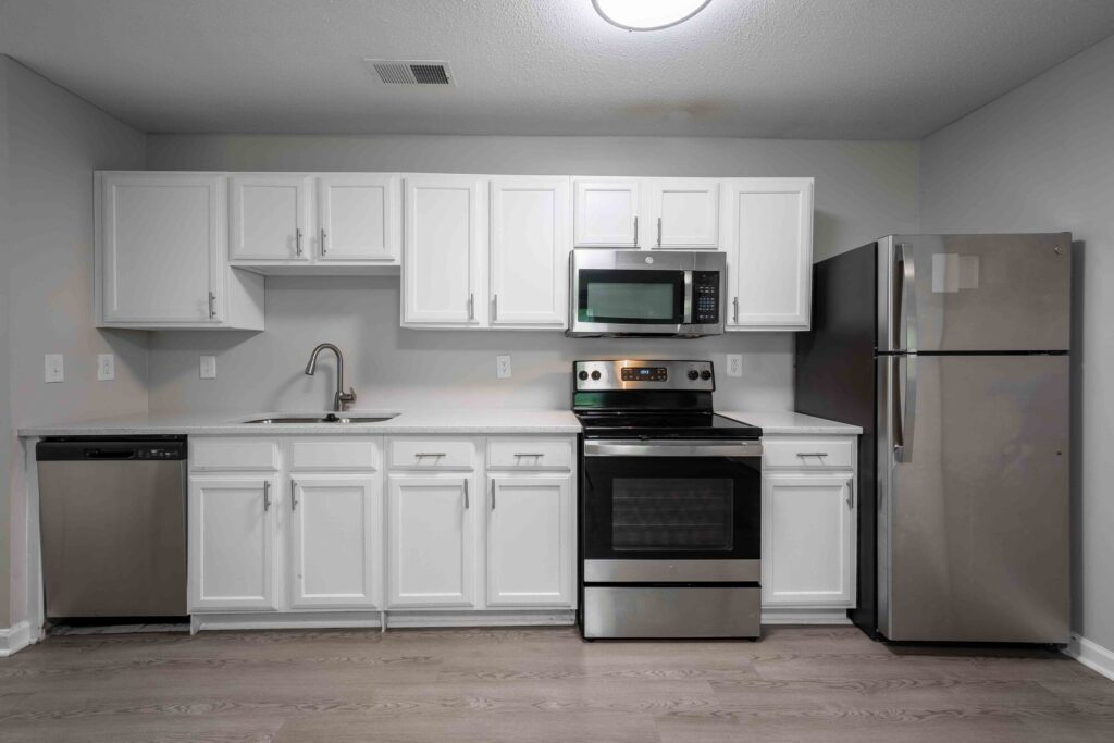 Open kitchen with white cabinets and stainless steel appliances