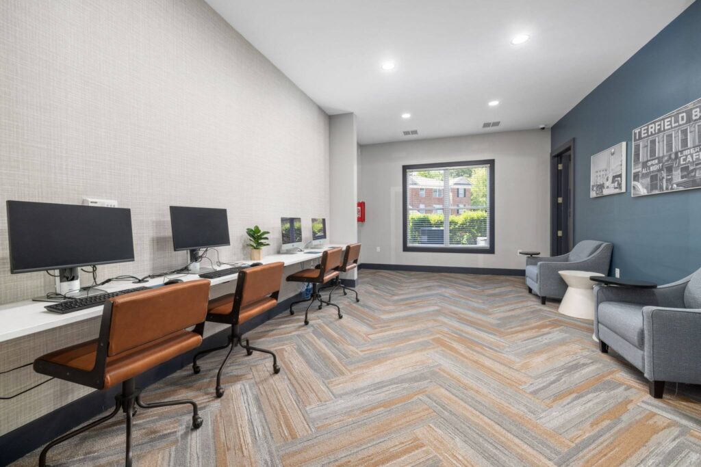 Indoor computer lab with carpet flooring, accent wall, window, lounge seating, and computers