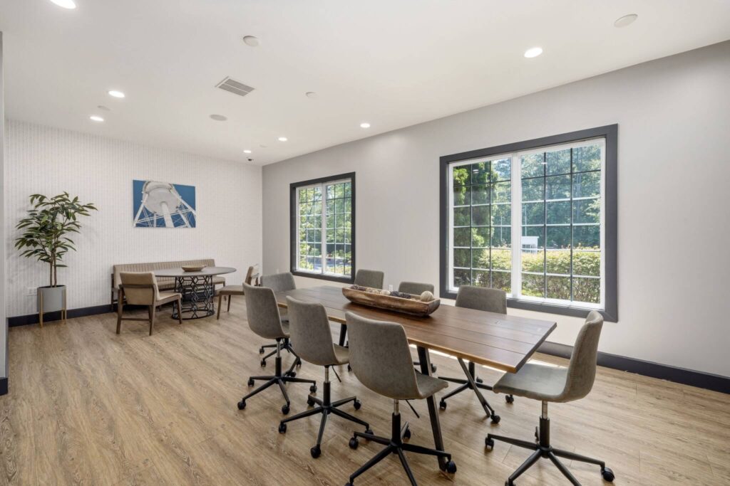 Indoor conference room with wood-style flooring, designer lighting, windows, and wall decor
